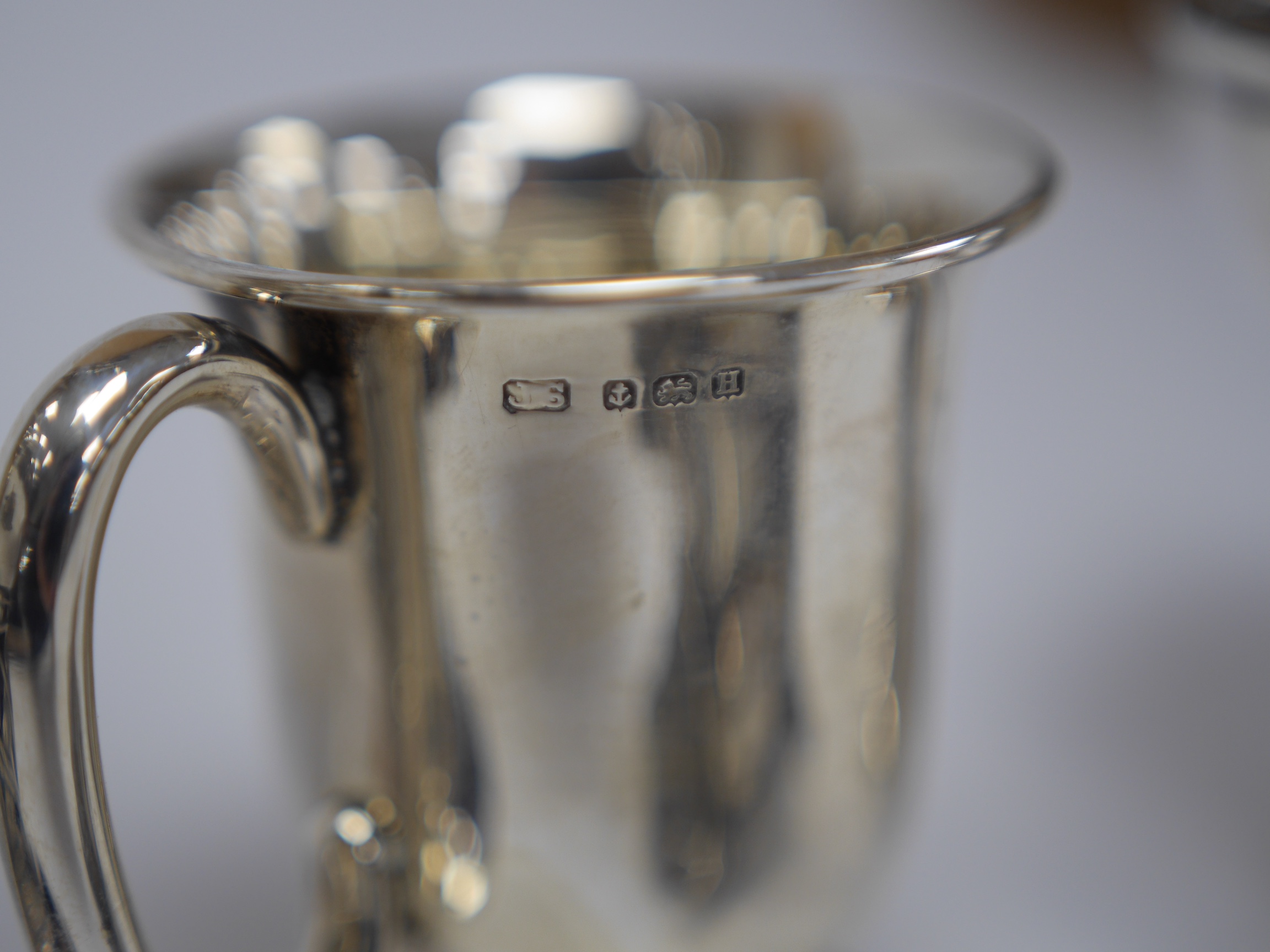 A George V silver spill vase, with pierced handles and stem, maker's mark rubbed, Birmingham, 1930, 16.6cm, together with a small silver tri-handled pedestal bowl, a small silver mug and Hanau white metal boat shaped sal